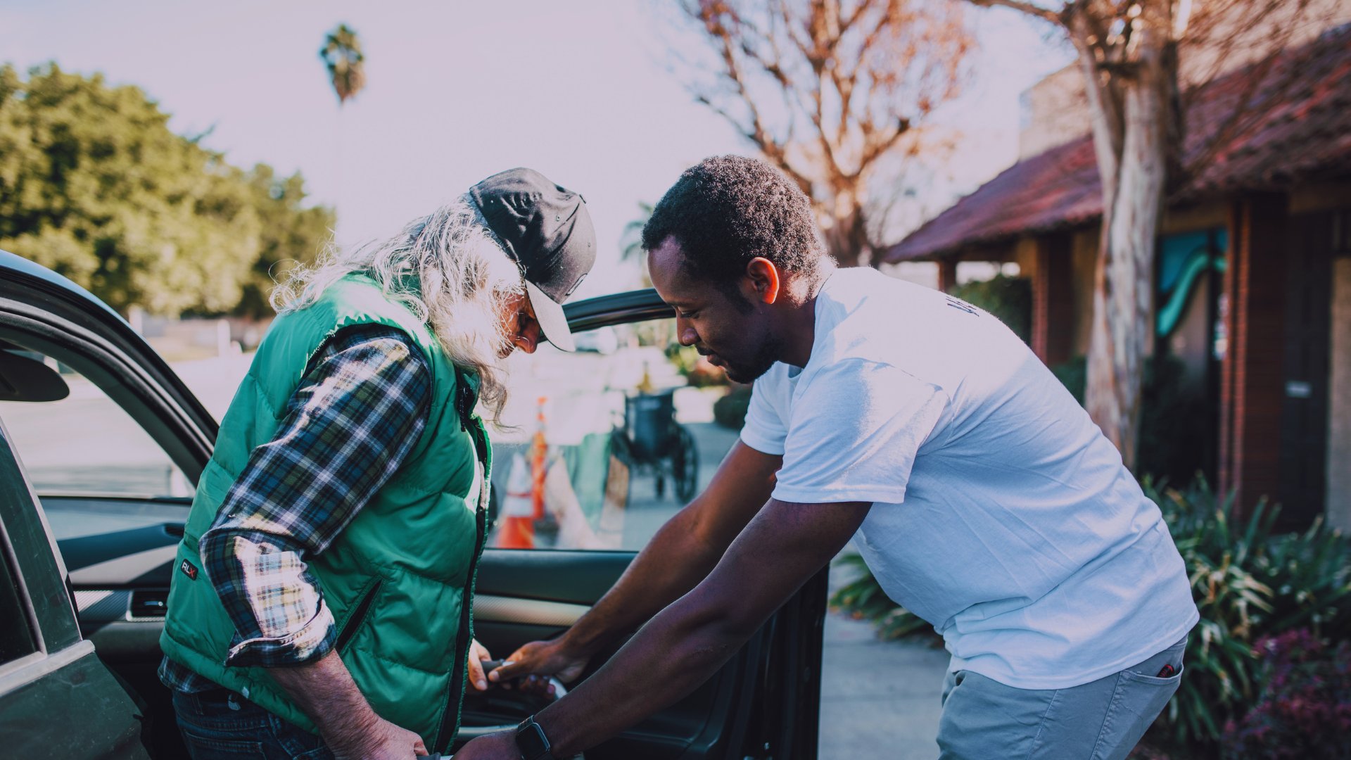 A volunteer helping an older adult at a car door